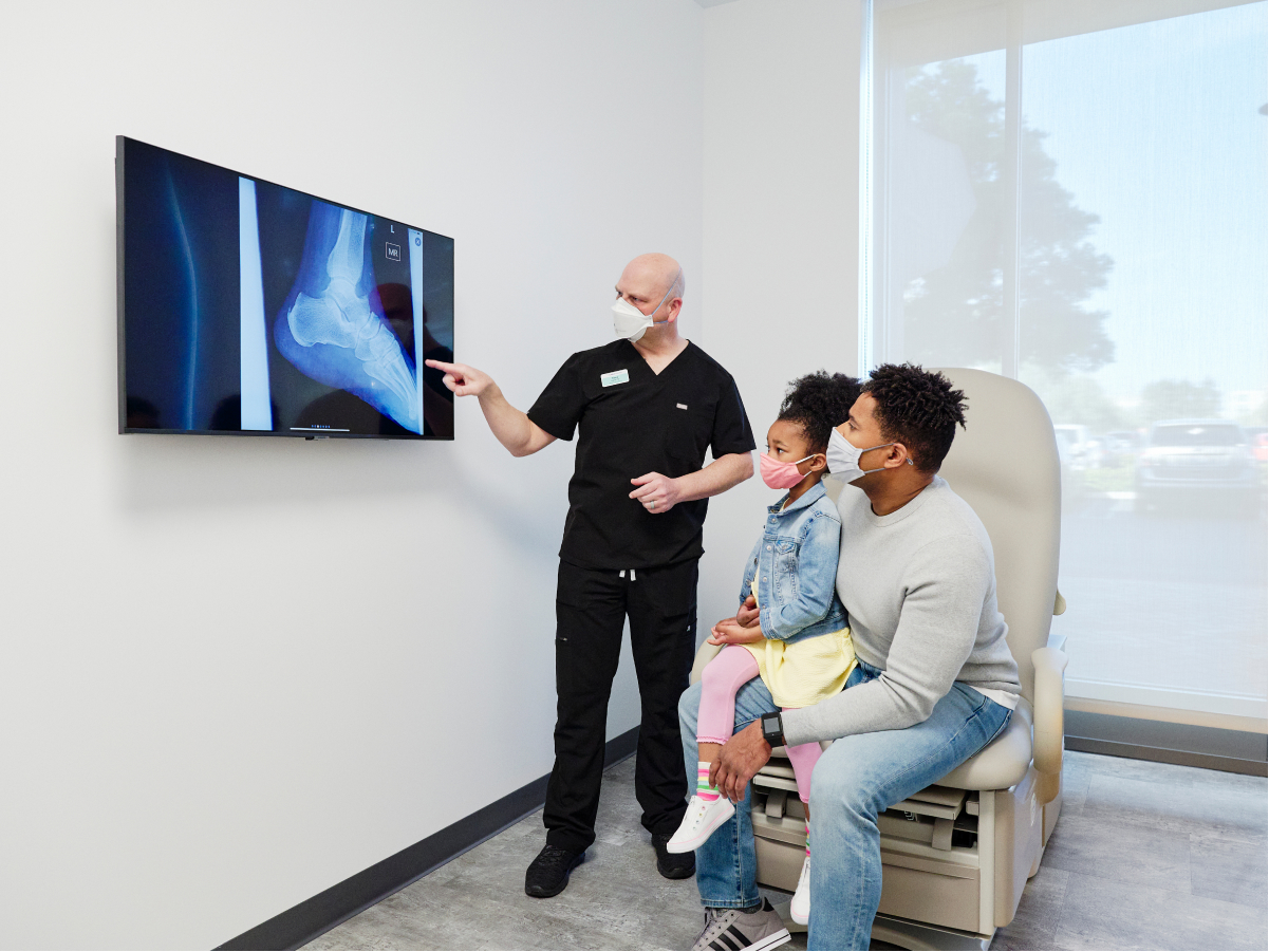 Father and daughter viewing x-rays with their doctor in a bright, clean exam room.
