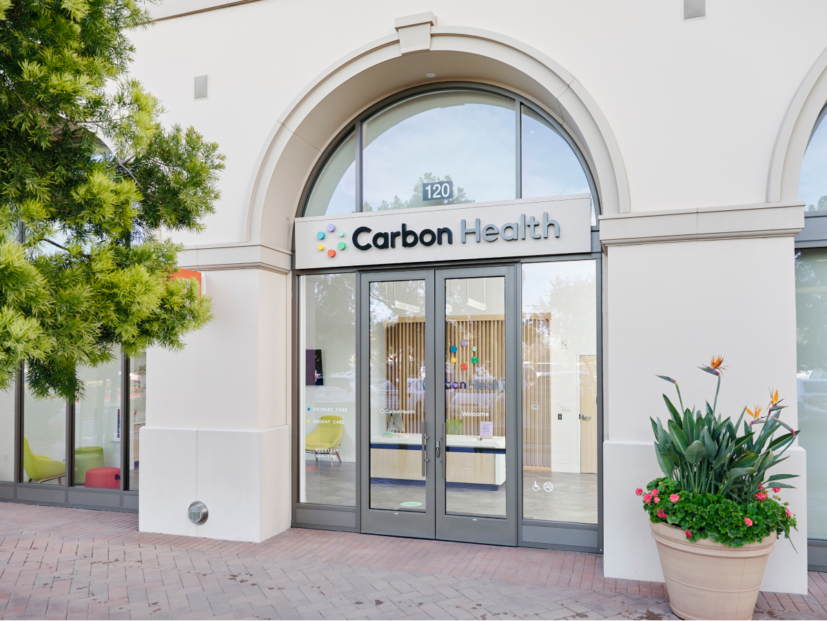 A Carbon Health clinic with a beautiful arched entry and large windows.